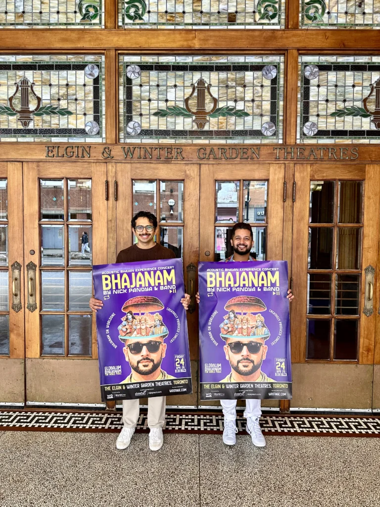 Manan Chhatiawala & Nick Pandya standing outside the Elgin & Winter Garden Theatres in Toronto holding the Bhajanam by Nick Pandya and Band poster for the Acoustic Bhajan Experience Concert on April 24, 2026.